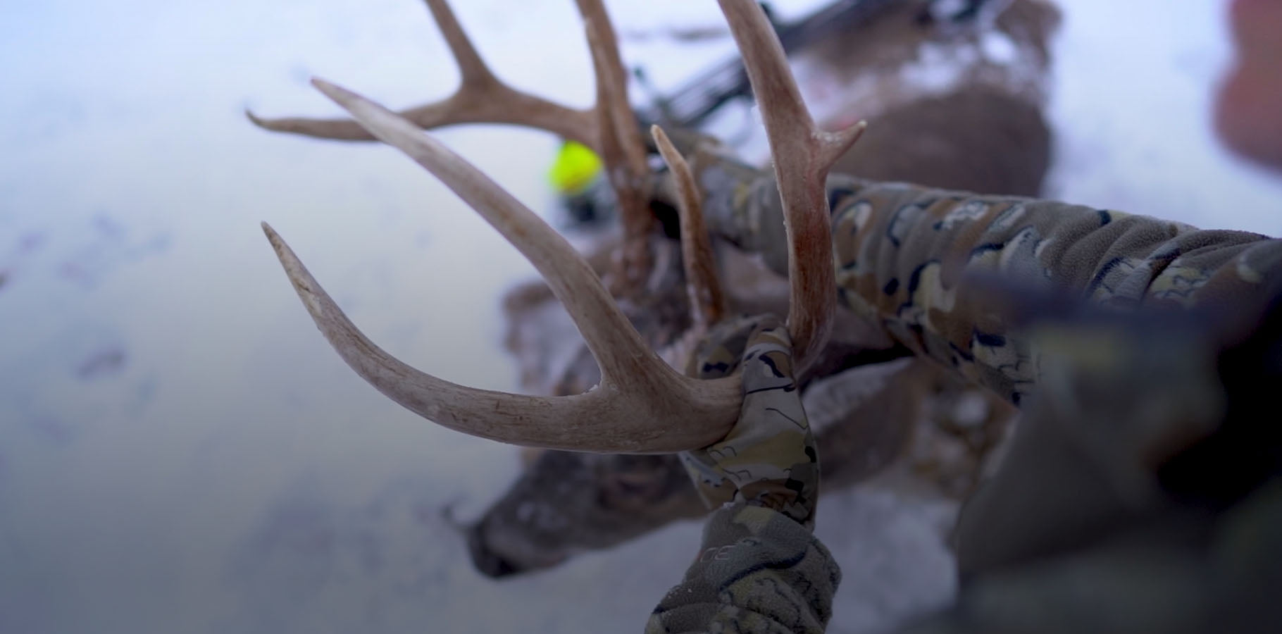 Over the Shoulder View of Hunter Wearing Proximity Hooded Insualted Jacket in Valo Camouflage Holding Harvested Whitetail Buck