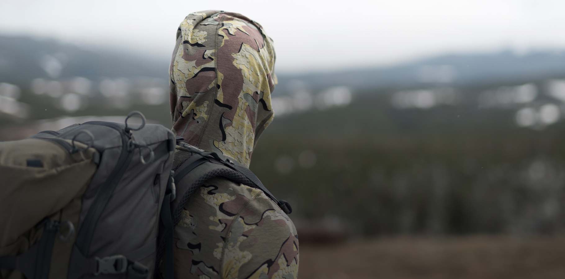 Back of Hunter Wearing Ultra Merino 120 LT LS Hoodie in Valo Camouflage Highlighting NuYarn Merino Wool