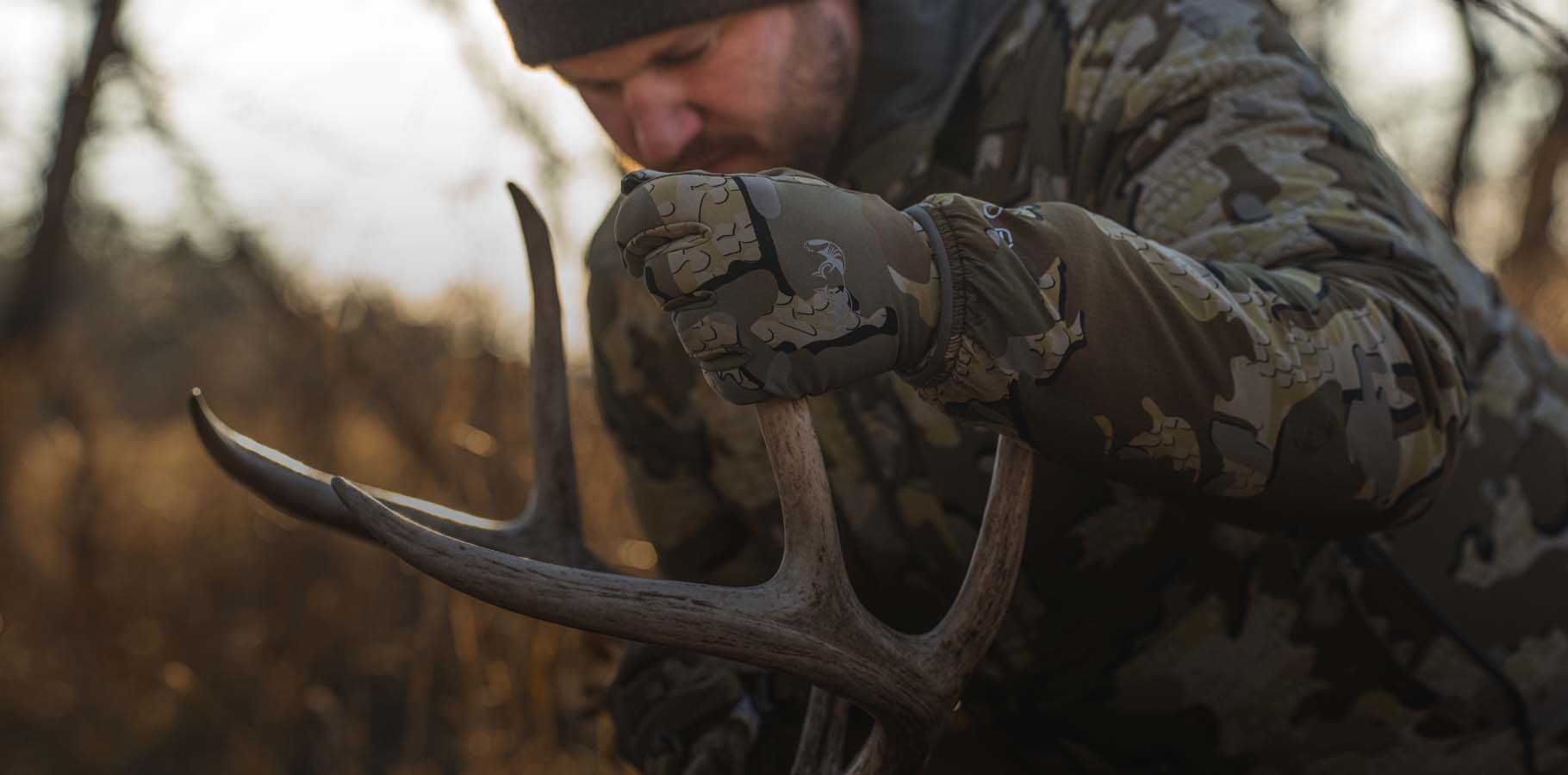 Front, Angled View of Hunter Wearing Valo Camouflage Holding Whitetail Buck