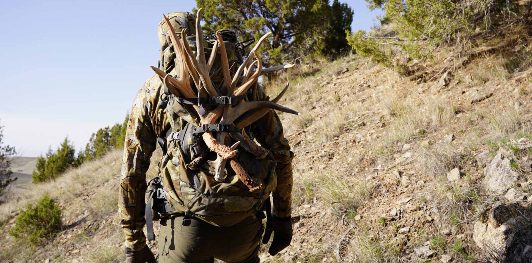 Back of Hunter in Valo Camouflage Packing Out Mule Deer Sheds