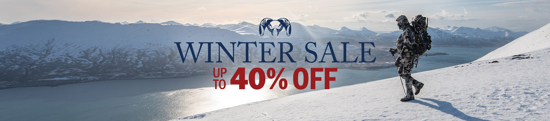 Hunter trekking through the snow with a breathtaking view of a mountain range and river winding below. Text reads: Winter Sale - Up to 40% Off