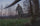 Hunter Holding Bow Walking Up to Harvested Whitetail Buck in Green Field Wearing Full Valo Camouflage