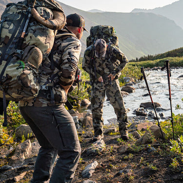 Two male hunters in head to toe KUIU adjusting their KUIU  packs after crossing a river.