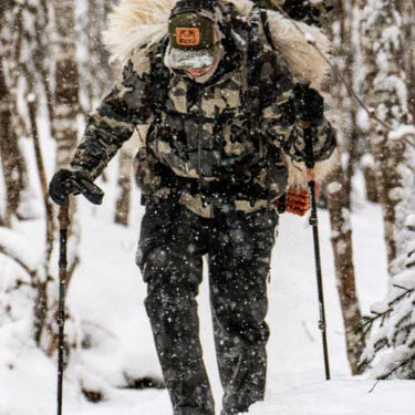 Male hunter in head to toe KUIU packing out in the snow.