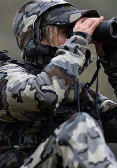 Woman glassing in the rain while wearing the Women's Chugach Rain Jacket in Vias Camouflage