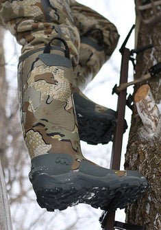 Hunter using a climbing stick on a tree, wearing KUIU Mud Boot in Valo Camouflage