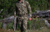 Hunter standing in the meadow holding an aluminum treestand, wearing Encounter LT Shirt and Pant in Valo Camouflage