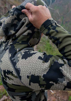 Rear, Angled View of Hunter Removing Hood on Peloton 240 Full Zip Hoodie in Verde Camouflage