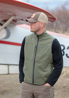 Side of Brendan Burns Wearing Guide DCS Vest in Olive Green Color in Front of Bush Plane